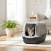 Gato atigrado usando cómodamente el arenero cubierto para gatos en un salón, mostrando su amplitud y diseño hogareño.