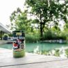 Envase de Tetra Pond Sticks con ingredientes naturales junto a un estanque, ideal para peces sanos y agua clara.